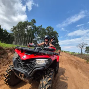 Casal em quadriciclo vermelho na estrada de terra durante passeio em Brotas