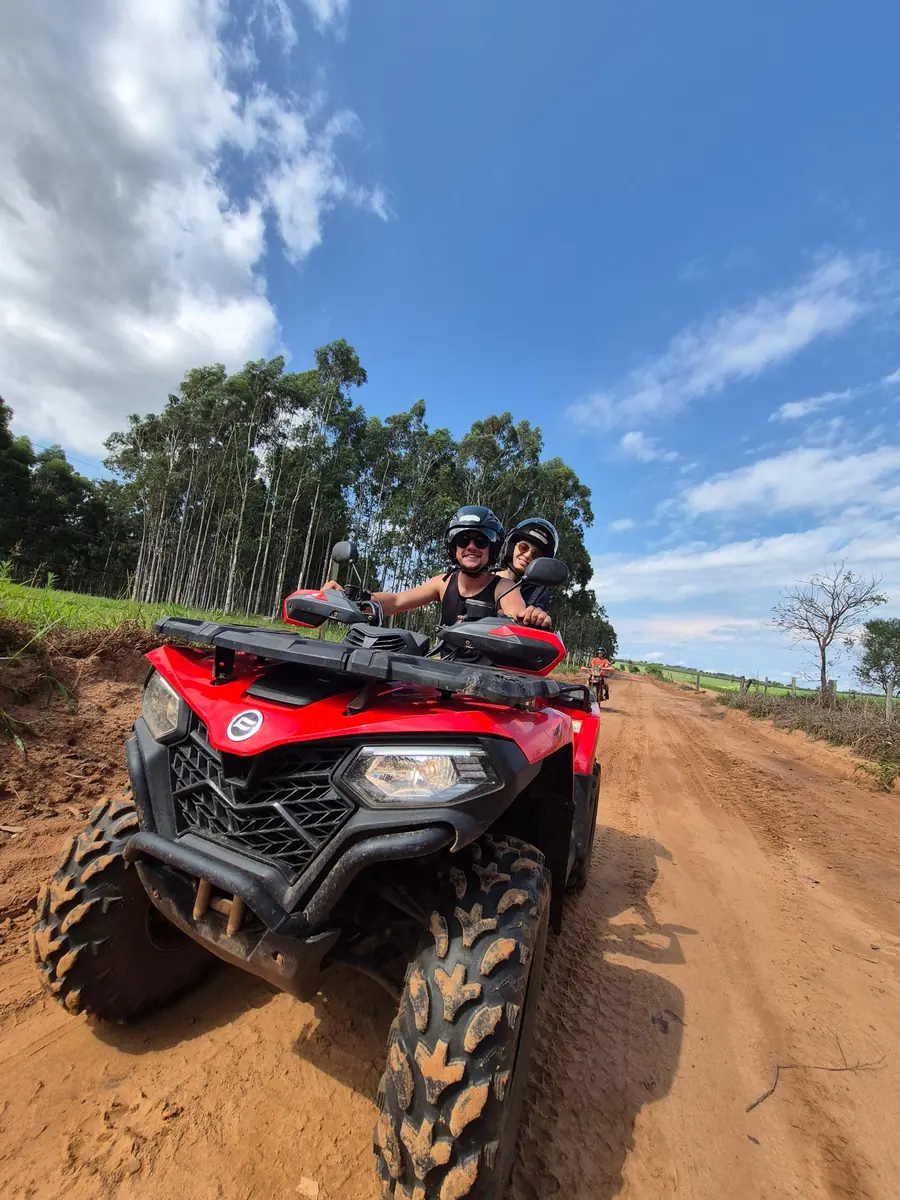 Couple on a red ATV on a dirt road during a tour in Brotas