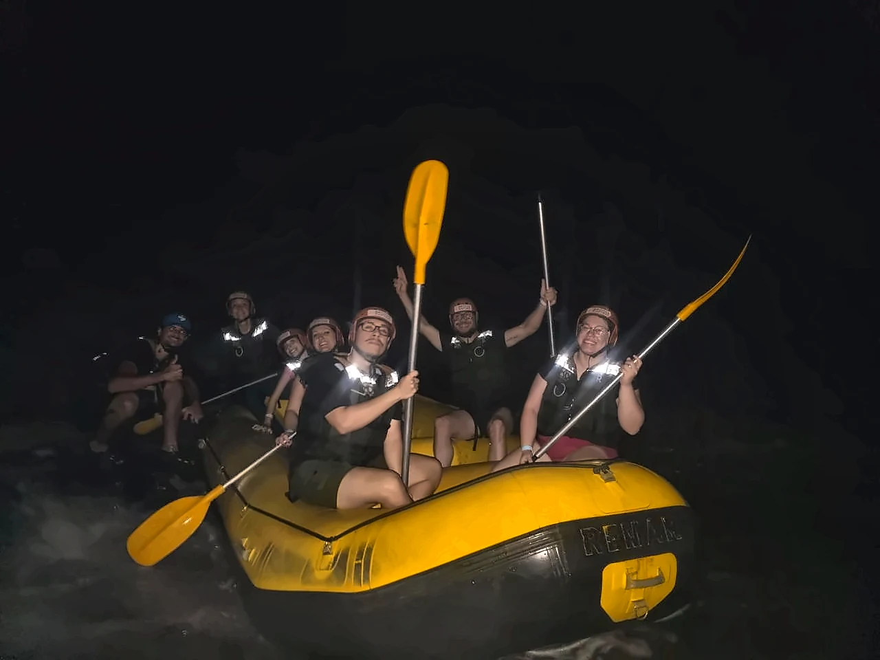 Group with paddles raised in the Night Rafting boat in Brotas