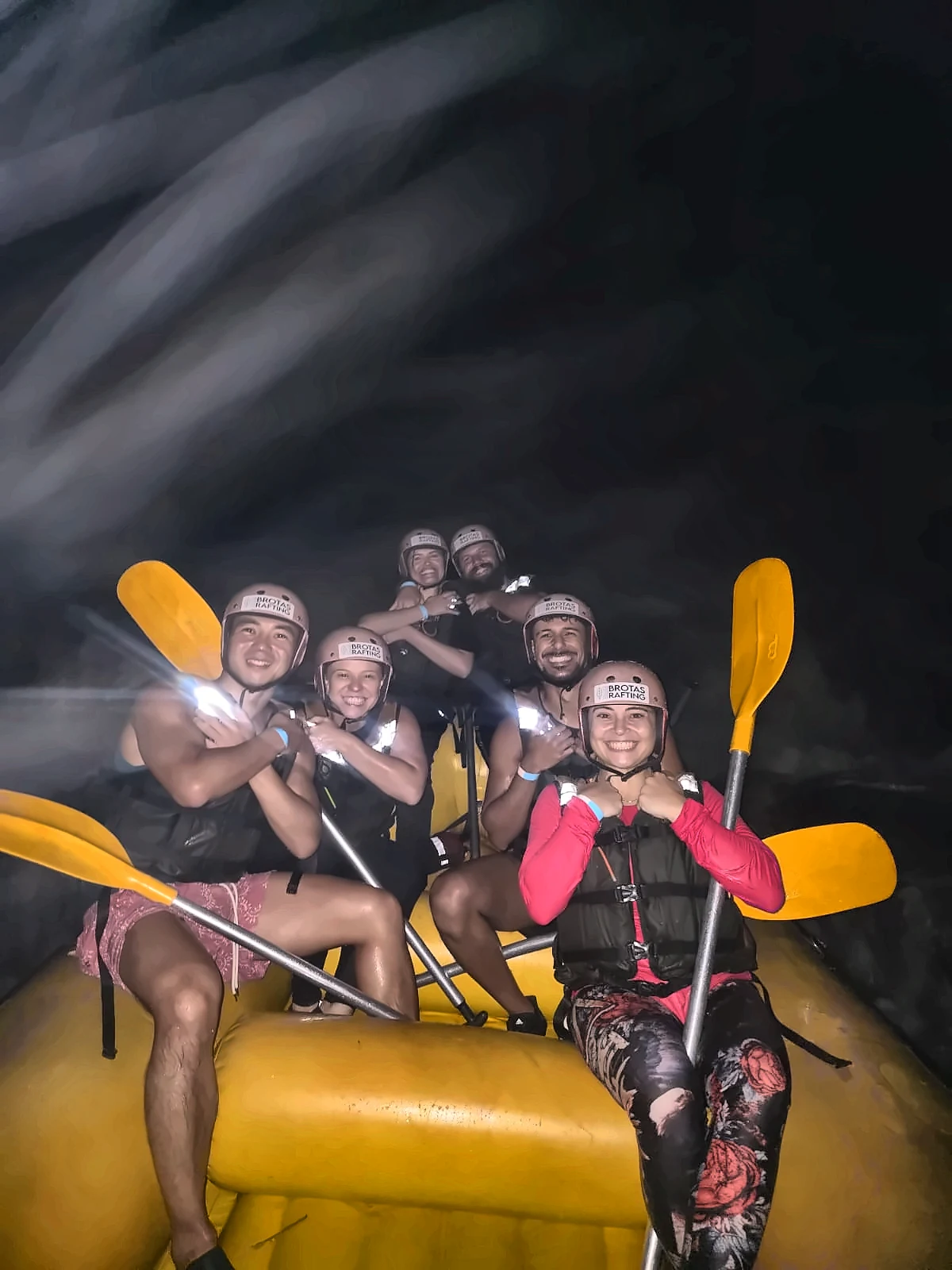 Friends with paddles at the bow of the boat during Night Rafting on a full moon night