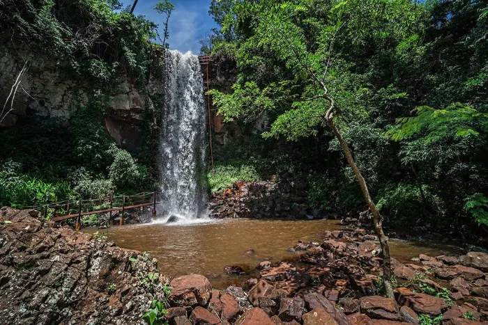 Cachoeira alta caindo em poço avermelhado na Cachoeira 3 Quedas, em Brotas